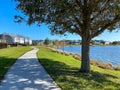 A curved sidewalk next to a lake that is a walking path in back of homes in Laureate Park