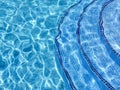 Curved steps into swimming pool, view from above through water on blue mosaic tiles. Distortion. Refraction Royalty Free Stock Photo