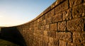 Curved stone wall at sunset, showcasing rustic texture and natural beauty. Ideal for architectural, landscape, and design projects Royalty Free Stock Photo