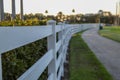 Curved white wooden fence alongside a grassy