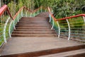 Curving ascending hillside planked stairway with colorful railing
