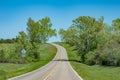 A curving asphalt road ascending a hill on a day in spring Royalty Free Stock Photo