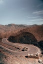 Curving through Atlas mountains, an intricate road winds, revealing the untamed beauty of the rugged terrain, promising an