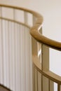 Curving brass railing on white metal pickets against white wall