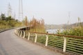 Curving footbridge along grassy woody riverside in sunny winter