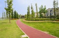 Curvous red-painted path in lawn along fenced villas on sunny summer day