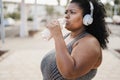 Curvy black woman drinking after jog routine outdoor at city park - Focus on face