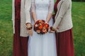 Curvy bride and bridesmaids are holding beautiful colorful bouquet with orange, red and pink peonies and roses. Wedding autumn Royalty Free Stock Photo