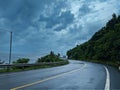 A curvy coastal moutain road after the rain with cloudy stormy cloud left is sea ocean right is the mountain Royalty Free Stock Photo