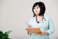 Curvy female nurse stands still writes the results by pen at paper, in medical lab coat with stethoscope around her neck