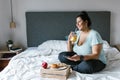 Curvy latin girl with smartphone having breakfast and drinking orange juice in bed in Latin America, plus size woman Royalty Free Stock Photo