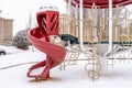 Curvy red slide of a neighborhood playground on a scenic snowy winter setting