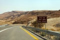 Curvy sandy road on a highway that runs along the Dead Sea from one side and Edom Mountains at Arava Desert from the other in