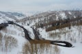 Curvy windy road in snow covered mountain hill. Top down aerial view. Scenic winter background captured from above Royalty Free Stock Photo