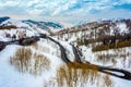 Curvy windy road in snow covered mountain hill. Top down aerial view. Scenic winter background captured from above Royalty Free Stock Photo