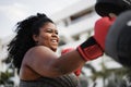 Curvy woman and personal trainer doing boxing workout session outdoor - Focus on face