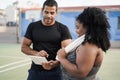 Curvy woman talking with her personal trainer while checking tech clipboard outdoor - Sport and plus size people concept - Focus