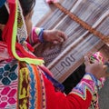 Cusco, Peru - 1 July, 2022: A Quechua lady weaves traditional Andean textiles using alpaca wool