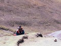 A Peruvian man lying on the ground at the foot of a mountain on a sunny day in Cusco Peru.