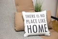Cushions on a sofa with a text There is no place like home, living room interior design details