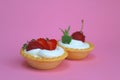 Two tartlets with cream and strawberries on a pink background Royalty Free Stock Photo