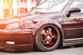 Custom brown forged wheels on a low tuned stance car who stays on a street. dirty Lowrider on a air suspension at sunny day Royalty Free Stock Photo