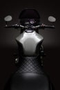 Custom caferacer motorbike on dark background with its headlight on.