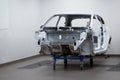 Custom car being build in workshop. Sports car body, car frame is assembled by mechanics. Metallic auto chassis in the air, car