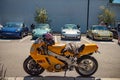 Custom yellow FZR400 motorcycle parked in front of sports cars in a parking lot