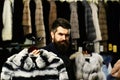 Customer with beard presents furry coats. Businessman with expensive overcoats Royalty Free Stock Photo