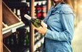 Customer buying white wine or sparkling drink. Alcohol aisle in store or supermarket. Woman holding bottle. Royalty Free Stock Photo