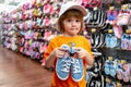 Customer child holdind shoes, shopping at supermarket, kids shoes store.