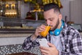 Customer drinking juice and reading articles and posts on his social media page outside of brazilian bakery. Concept of clientele