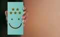 Customer Experience Concept. Happy Client giving Positive Review on Paper Card. Feedback a Happy Face Icon and Five Star Rating . Royalty Free Stock Photo