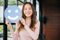 Woman smiling showing excellent rating with smiley face icon on blue circle paper Royalty Free Stock Photo