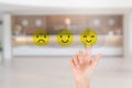 Hand pressing smile emotion icons for giving best service ranking with blurry image of hotel lobby reception in background. Royalty Free Stock Photo