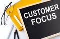 CUSTOMER FOCUS text on the blackboard with notepad , pen, pencil Royalty Free Stock Photo