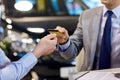 Customer giving credit card to car dealer in salon Royalty Free Stock Photo