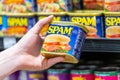 Customer hand holding a tin can of Spam brand meat