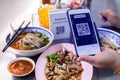 Customer hand using smart phone to scan QR code tag with blur noodles or chinese food and blurry soft drik to accepted generate