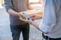 Customer hands appending signature in mobile phone, man receiving parcel post box from courier with delivery service man, express