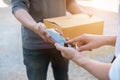 Customer hands appending signature in mobile phone, man receiving parcel post box from courier with delivery service man, express Royalty Free Stock Photo