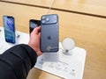Customer holds blue iPhone 17 Pro Max in electronics store, examining latest tech on display with security tag Royalty Free Stock Photo