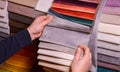 The customer looks at and selects the color fabric she likes, selects the fabric from the fabric swatches for her new sofa.