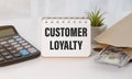 customer loyalty, text on white notepad sheet on wood background