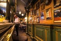 Customer making an order at bar counter, small restaurant with vintage interior, old paintings and posters