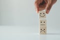 Customer satisfaction concept. Hand lifts smiling face and sad face icon on wood cube block.