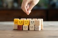 Customer selects a smiley face among blurred sad faces on a wooden cube