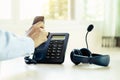 Hand picking up phone with headset and use telephone for communication helpdesk IT support or call