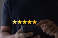 Customer service experience and business satisfaction survey concept. Man hand using mobile smartphone and give five star symbol Royalty Free Stock Photo